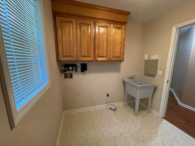 clothes washing area with hookup for a washing machine, cabinets, a textured ceiling, and electric dryer hookup