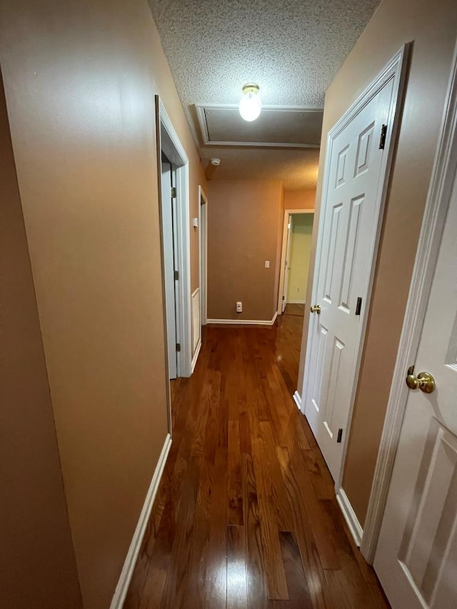 hallway with a textured ceiling and dark wood-type flooring