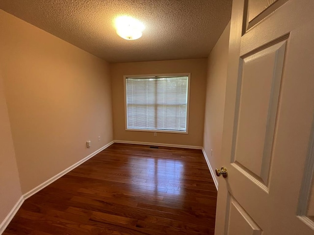 empty room with a textured ceiling and dark wood-type flooring