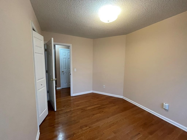 empty room with a textured ceiling and dark hardwood / wood-style flooring