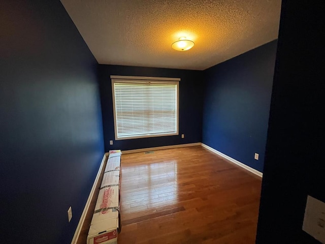 empty room with hardwood / wood-style flooring and a textured ceiling