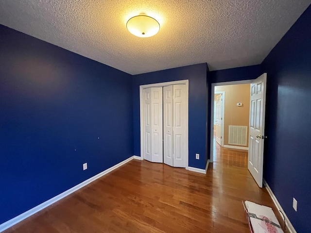 unfurnished bedroom with hardwood / wood-style flooring, a closet, and a textured ceiling