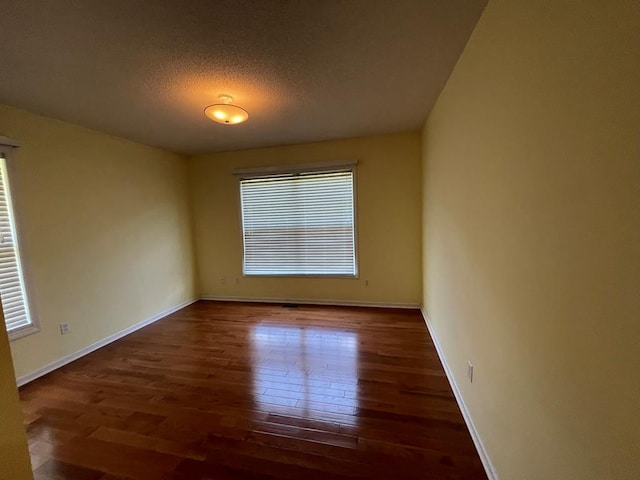 unfurnished room with dark hardwood / wood-style floors and a textured ceiling