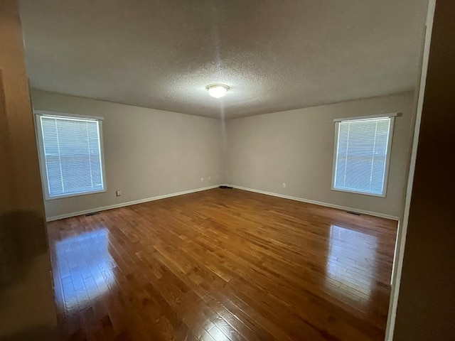 empty room with hardwood / wood-style flooring and a textured ceiling