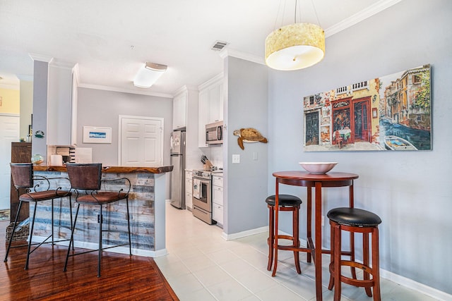 kitchen featuring white cabinetry, appliances with stainless steel finishes, a breakfast bar area, and kitchen peninsula