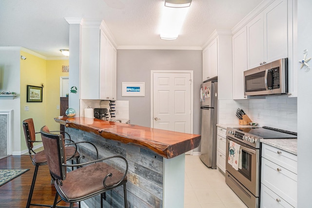 kitchen with stainless steel appliances, white cabinetry, tasteful backsplash, and a kitchen bar