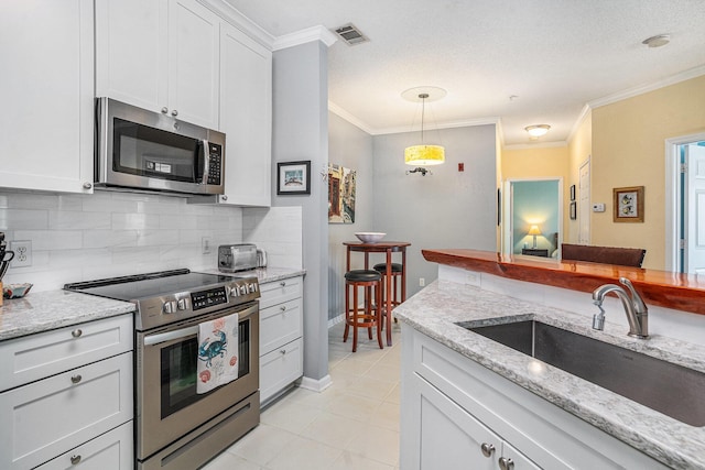 kitchen featuring sink, hanging light fixtures, white cabinets, and appliances with stainless steel finishes