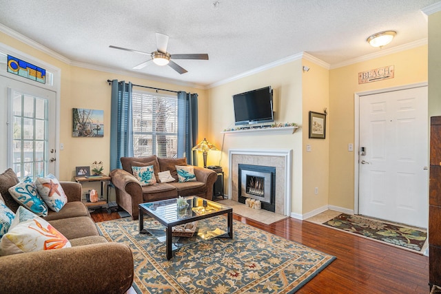 living room with ceiling fan, wood-type flooring, ornamental molding, and a textured ceiling