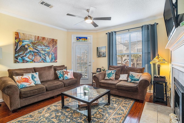 living room with ornamental molding, a tiled fireplace, and wood-type flooring