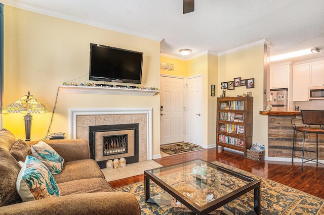 living room with ornamental molding, a textured ceiling, a fireplace, and dark hardwood / wood-style flooring