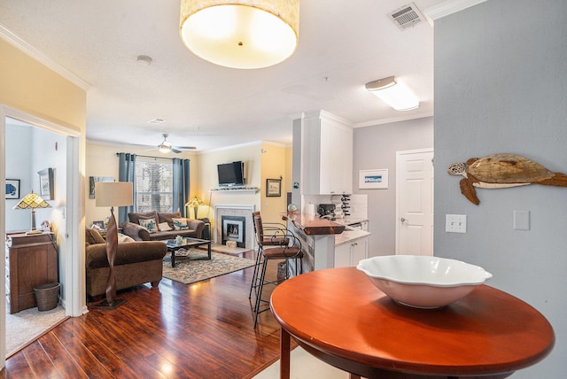 dining space with dark wood-type flooring, ceiling fan, and crown molding