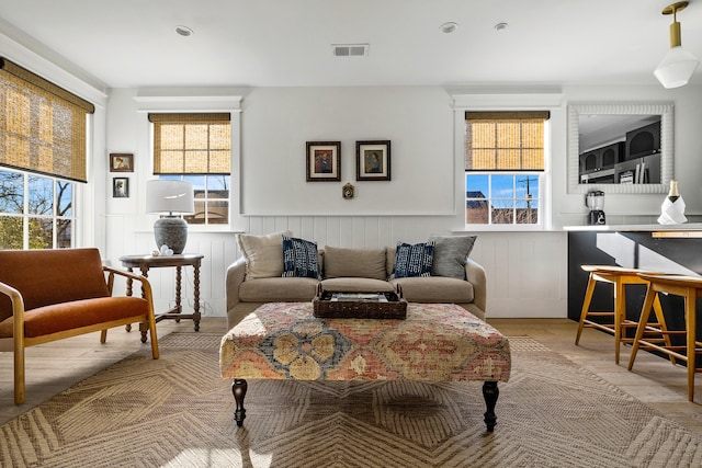 95 Line St, Charleston, SC 29403 - living area with light wood-type flooring, a wainscoted wall, plenty of natural light, and visible vents