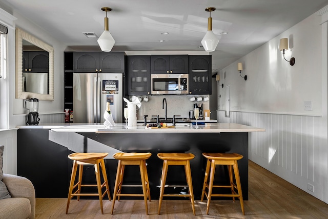 95 Line St, Charleston, SC 29403 - kitchen featuring a breakfast bar area, a wainscoted wall, wood finished floors, light countertops, and appliances with stainless steel finishes