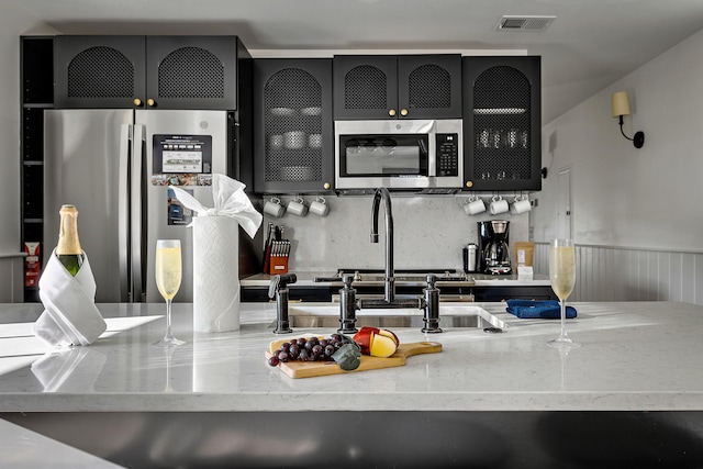 95 Line St, Charleston, SC 29403 - kitchen featuring appliances with stainless steel finishes, visible vents, glass insert cabinets, and light stone countertops