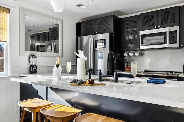 95 Line St, Charleston, SC 29403 - kitchen with tasteful backsplash, visible vents, appliances with stainless steel finishes, a breakfast bar, and dark cabinets