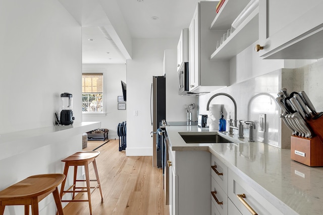 95 Line St, Charleston, SC 29403 - kitchen featuring a breakfast bar, light wood finished floors, light countertops, white cabinets, and a sink