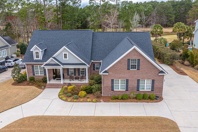 view of front of home featuring concrete driveway, a porch, a shingled roof, and brick siding