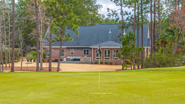 rear view of house with a shingled roof, a yard, a patio area, outdoor lounge area, and brick siding