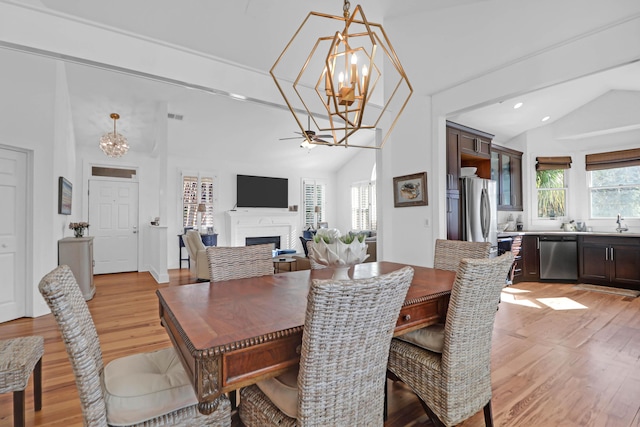 dining room with sink, light hardwood / wood-style floors, lofted ceiling, and an inviting chandelier