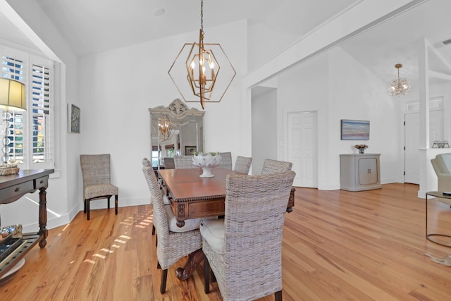 dining space featuring a notable chandelier, light hardwood / wood-style floors, and high vaulted ceiling