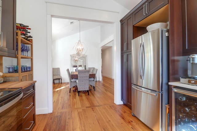 kitchen with wine cooler, stainless steel fridge, a chandelier, pendant lighting, and light hardwood / wood-style floors