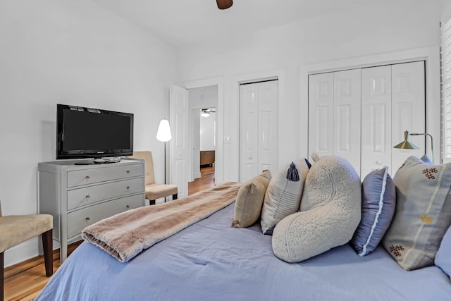 bedroom featuring ceiling fan, two closets, and hardwood / wood-style flooring