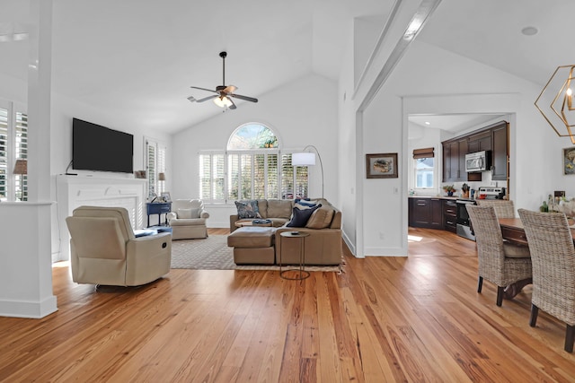 living room with beam ceiling, ceiling fan, high vaulted ceiling, and light wood-type flooring