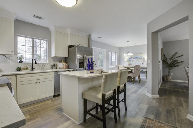 kitchen featuring appliances with stainless steel finishes, decorative light fixtures, sink, and a kitchen island