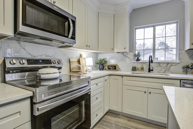 kitchen featuring appliances with stainless steel finishes, white cabinetry, backsplash, and sink