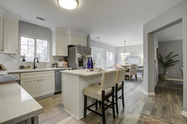 kitchen with sink, an inviting chandelier, hanging light fixtures, a kitchen island, and appliances with stainless steel finishes