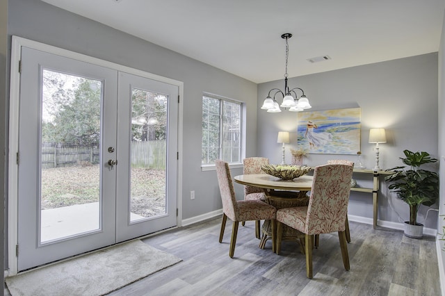 dining space featuring french doors, hardwood / wood-style floors, and a notable chandelier