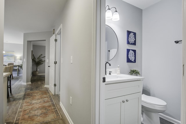 bathroom with toilet, vanity, and hardwood / wood-style floors