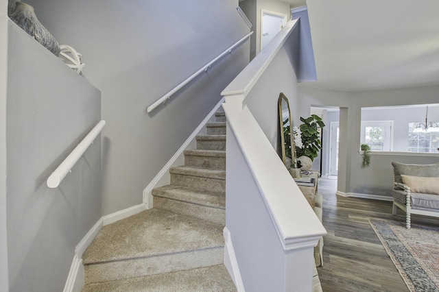 staircase featuring wood-type flooring and a chandelier