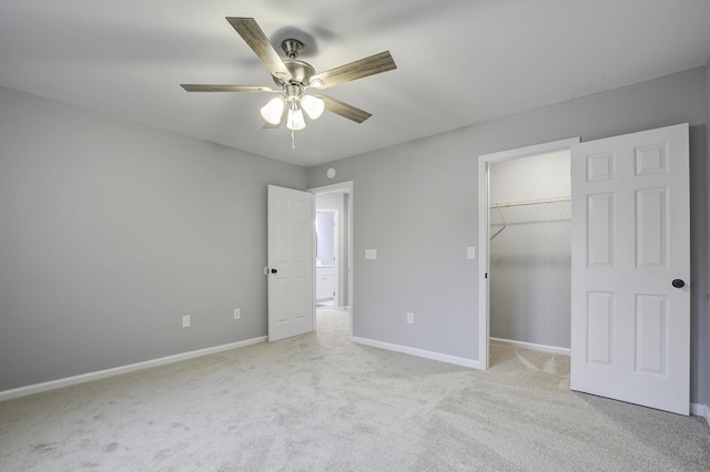 unfurnished bedroom featuring ceiling fan, light colored carpet, a closet, and a walk in closet