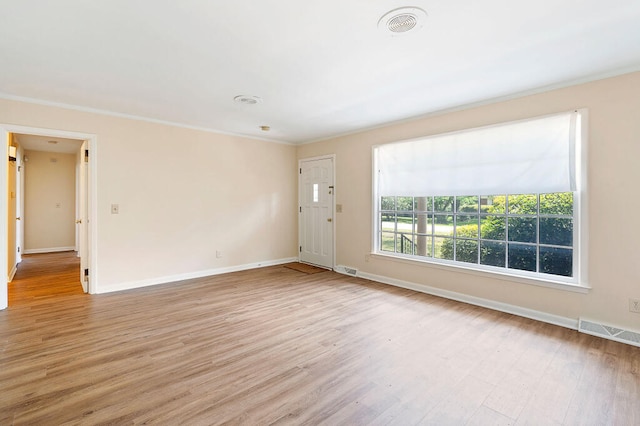 unfurnished living room featuring light wood-style flooring, baseboards, visible vents, and ornamental molding