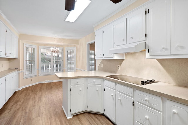 kitchen with black electric stovetop, under cabinet range hood, a chandelier, a peninsula, and white cabinets