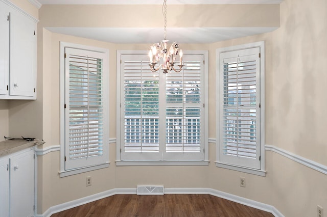 unfurnished dining area with visible vents, baseboards, an inviting chandelier, and dark wood finished floors