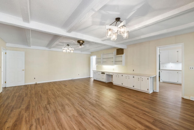 unfurnished living room with wood finished floors, baseboards, built in study area, beam ceiling, and a chandelier