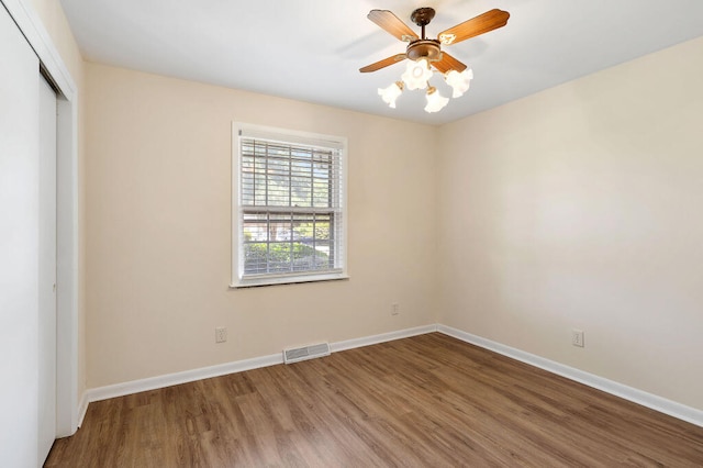 unfurnished bedroom featuring a ceiling fan, wood finished floors, visible vents, baseboards, and a closet