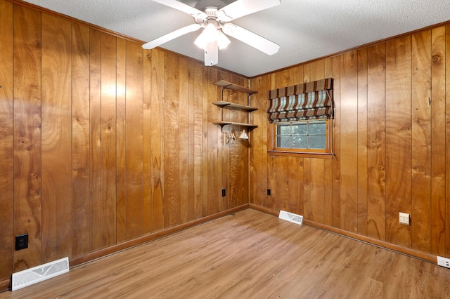 empty room with a textured ceiling, wood finished floors, visible vents, and ceiling fan