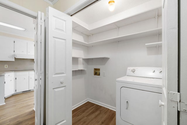 laundry area featuring laundry area, washer / dryer, baseboards, and wood finished floors