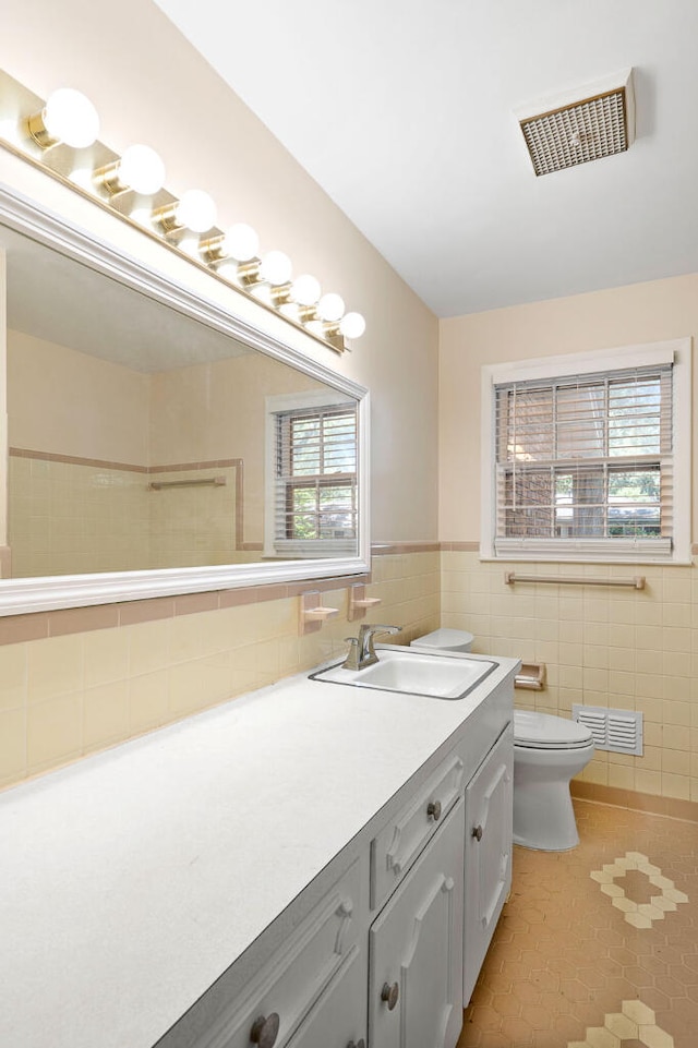 bathroom with visible vents, toilet, tile walls, and vanity