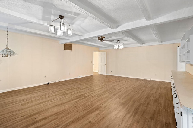 unfurnished living room featuring beamed ceiling, wood finished floors, and a textured ceiling