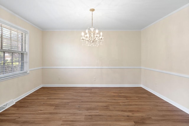 spare room with wood finished floors, baseboards, visible vents, an inviting chandelier, and crown molding