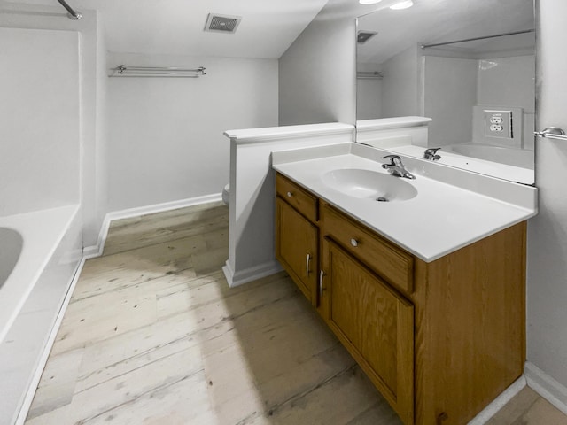 bathroom featuring vanity, wood finished floors, baseboards, toilet, and shower / bath combination