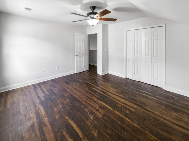 unfurnished bedroom featuring dark wood-style flooring, baseboards, a ceiling fan, and a closet
