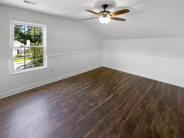 bonus room with dark wood-type flooring, a ceiling fan, a wainscoted wall, vaulted ceiling, and baseboards