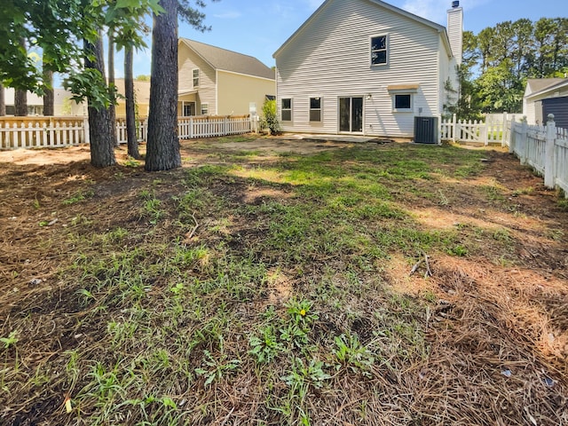back of property with central air condition unit, a chimney, and a fenced backyard