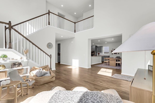 living room with hardwood / wood-style floors and a towering ceiling