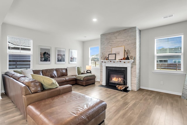 living room with light hardwood / wood-style floors and a stone fireplace